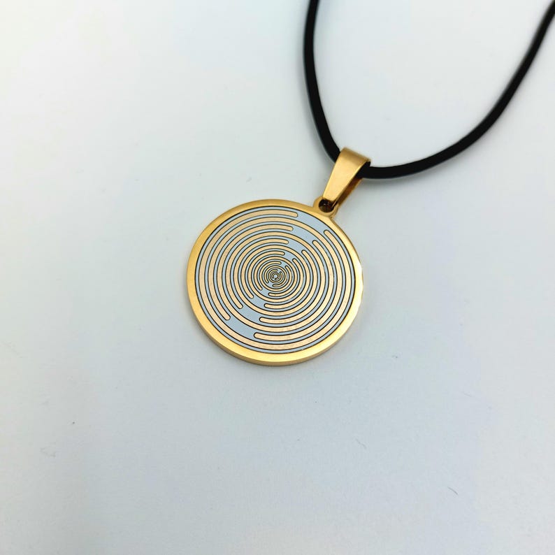 May include: A gold necklace with a round pendant featuring a white and gold concentric circle design.