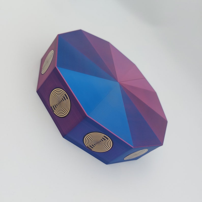 May include: A purple and blue geometric shaped box with gold spiral designs on each side.