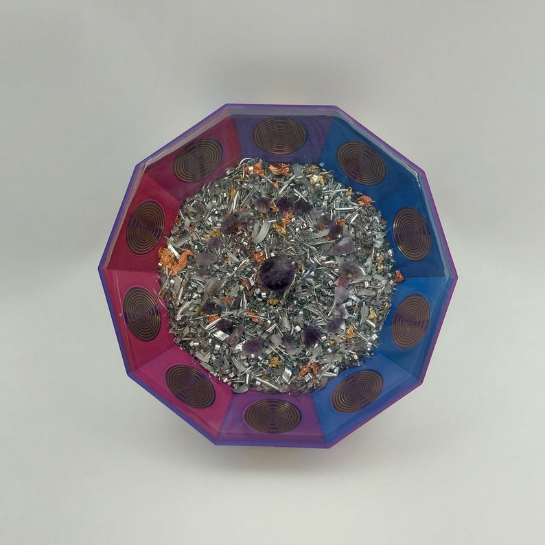 May include: Octagonal bowl with a pink and blue swirl design. The bowl is filled with silver metal shavings, amethyst crystals, and gold flakes.