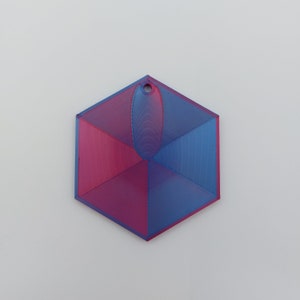 May include: A 3D printed hexagonal ornament with a blue and pink gradient. The ornament has a small hole at the top for hanging.