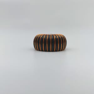 May include: A black and copper colored coil with a rounded shape.