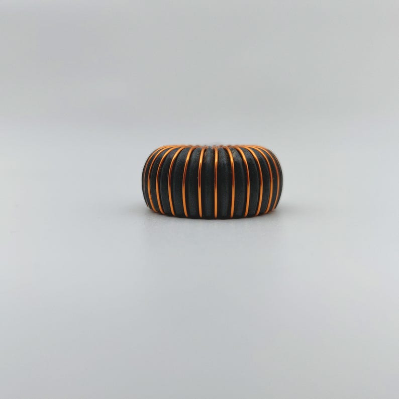 May include: A black and copper colored coil with a rounded shape.