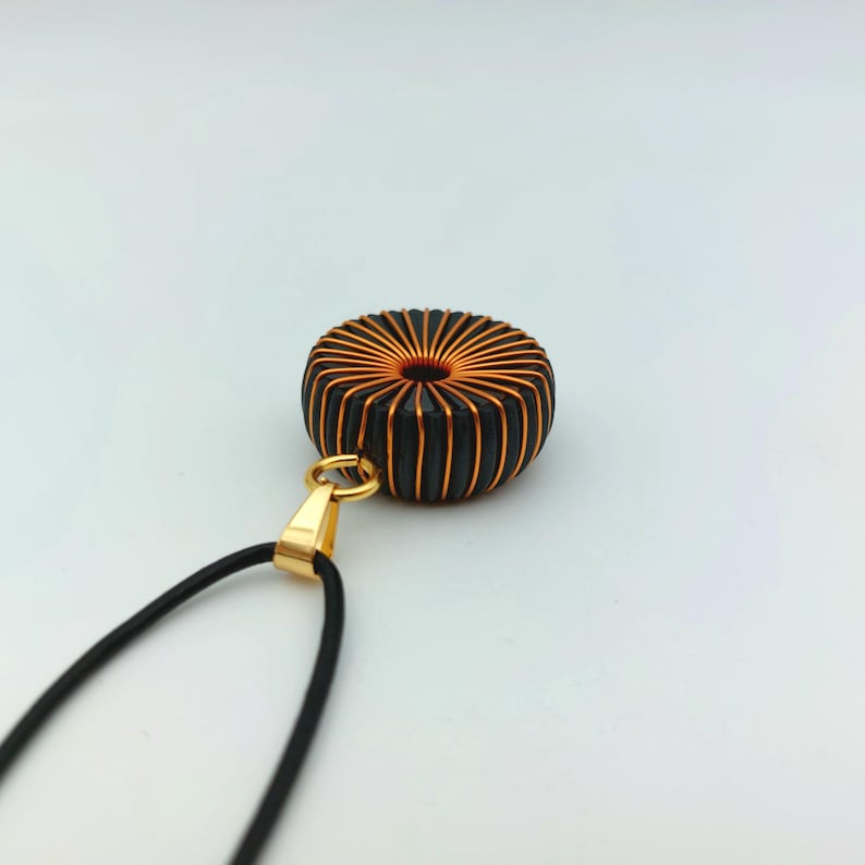 May include: A black and copper wire coil pendant necklace with a gold-colored clasp and a black leather cord.