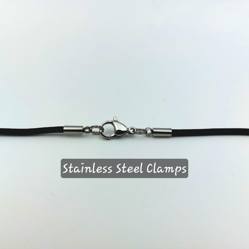 Puede incluir: Un collar de cord&oacute;n negro con abrazaderas de acero inoxidable. "Stainless Steel Clamps" est&aacute; escrito en negro debajo del collar.