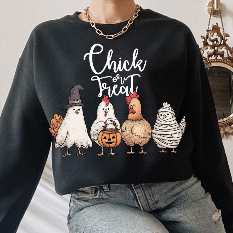 May include: Black sweatshirt with the text "Chick or Treat" in white script. The sweatshirt features four cartoon chickens dressed in Halloween costumes: a witch, a chicken holding a jack-o'-lantern, a regular chicken, and a mummy chicken.