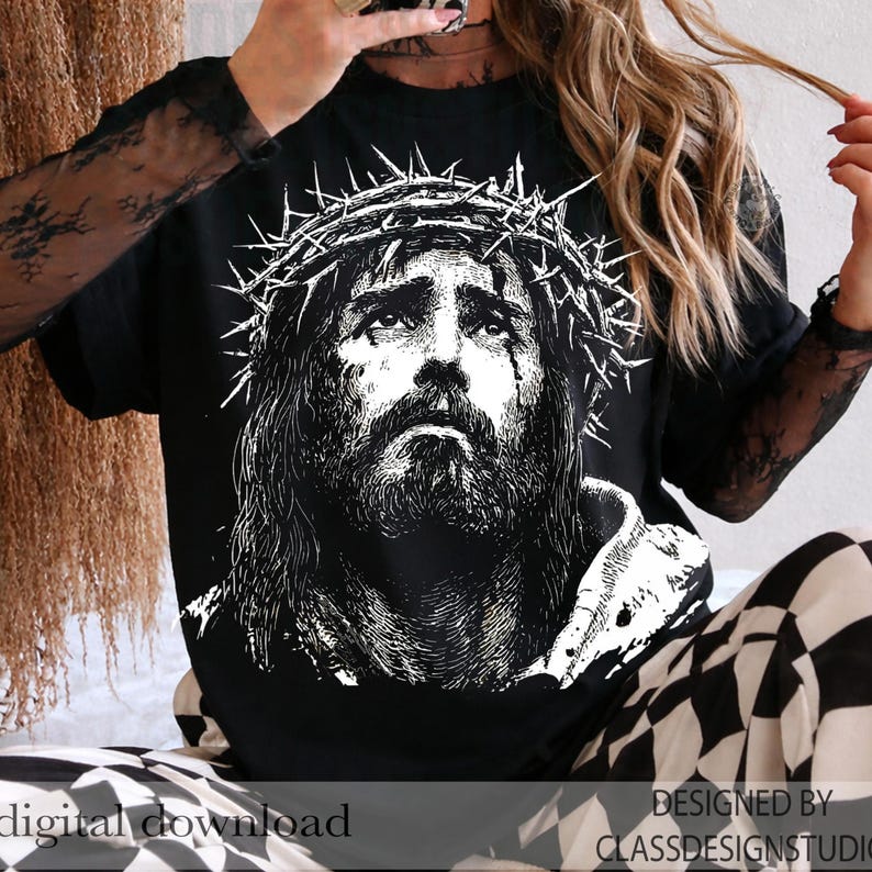 Pu&ograve; includere: T-shirt nera con un'illustrazione dettagliata in bianco e nero di un uomo con una corona di spine. L'immagine ha un'estetica vintage e usurata. Le parole "download digitale" e "progettato da classdesignstudio" sono visibili.