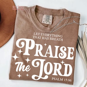 May include: A brown t-shirt with a white graphic that says "Let everything that has breath Praise the Lord" and "Psalm 15:06".