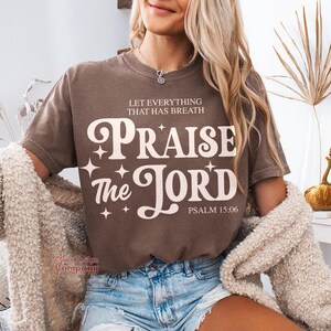 May include: A brown t-shirt with the text "Let everything that has breath Praise the Lord Psalm 15:06" in white lettering.