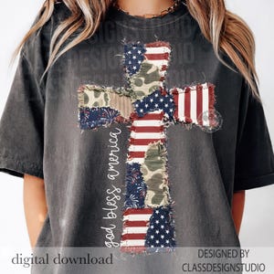 May include: Dark gray t-shirt featuring a cross design made of patches with American flag and camouflage patterns. The words "god bless america" are written vertically on the left side of the cross. The words "digital download" are at the bottom.