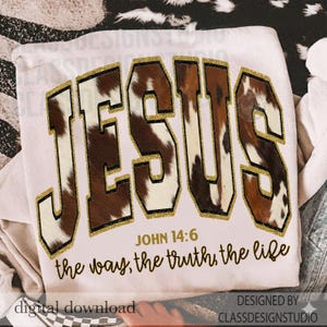 May include: Cream-coloured sweatshirt featuring the word "JESUS" in a bold, cowhide-patterned font with gold glitter edging. The text "JOHN 14:6 the way, the truth, the life" is printed below the main text.