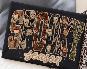 May include: A black t-shirt featuring the word SPOOKY in large block letters filled with various horror movie character illustrations and the word season written in a cursive font below, all outlined with a faux-stitched effect.