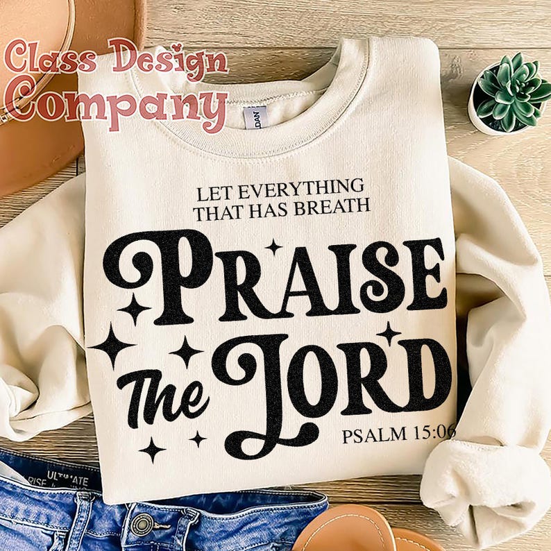 May include: A beige sweatshirt with the text "Let everything that has breath Praise the Lord" in black lettering. The text is in a retro font style with stars around it. The text "Psalm 15:06" is also included in black lettering.