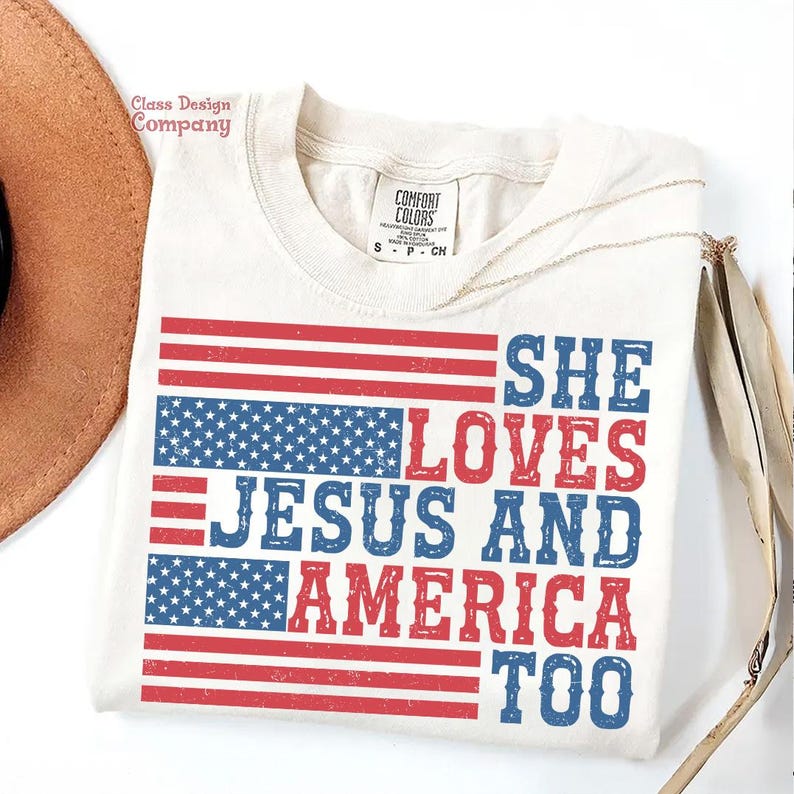 May include: A white t-shirt featuring a distressed American flag design and the text "She Loves Jesus and America Too" in blue and red.