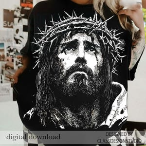 Pu&ograve; includere: T-shirt nero con un'illustrazione in bianco e nero di una persona con una corona di spine. Il design ha un aspetto vintage e usurato. Il testo in basso dice "digital download" e "DESIGNED BY CLASSDESIGNSTUDIO."