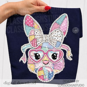 以下が含まれることがあります： カラフルなパッチワークのウサギのデザインが施された濃いネイビーブルーの生地。ウサギはハート型のメガネとリボンをしており、パールで装飾されています。「デジタルダウンロード」と「CLASSDESIGNSTUDIOによるデザイン」の文字が見えます。
