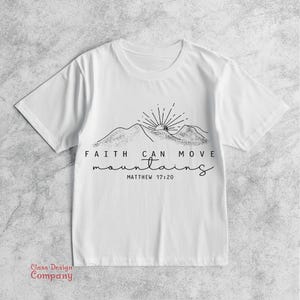 May include: White t-shirt with a black graphic of mountains and a sun. The text reads "Faith can move mountains" and "Matthew 17:20".