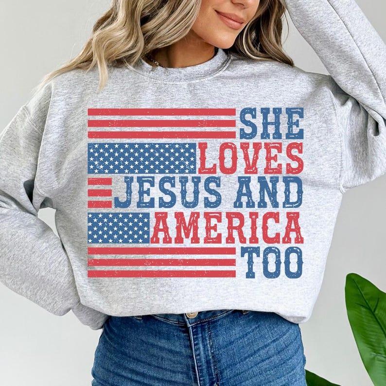 May include: Grey sweatshirt with a distressed American flag design and the text "She Loves Jesus and America Too".