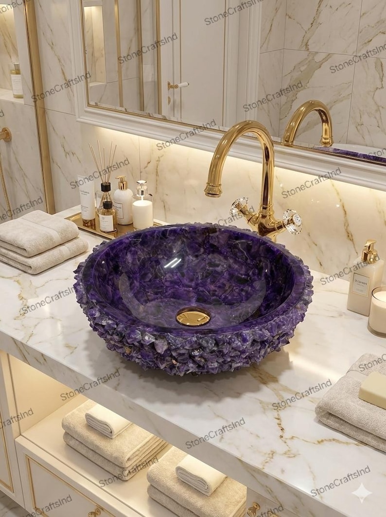 May include: A luxurious purple stone bathroom sink with a gold faucet. The sink has a textured, crystal-like exterior and a smooth interior. The faucet has crystal handles. The sink is set on a white marble countertop.