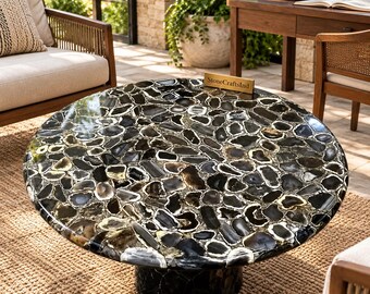 May include: A round coffee table featuring a polished surface composed of numerous black and grey agate stone slices. The table has a cylindrical base covered in matching stone pieces and includes a small gold plaque labeled StoneCraftsInd.
