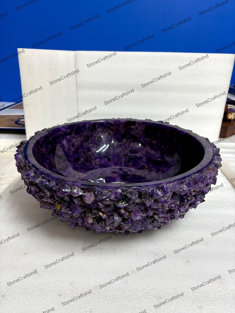 May include: A deep purple amethyst bowl with a rough, textured exterior and a smooth interior. The bowl is a rich shade of purple, showcasing the natural beauty of the gemstone. The bowl is a decorative item.