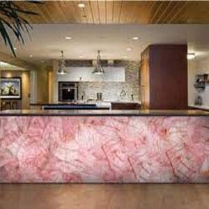 May include: A kitchen countertop with a pink and white marble-like surface. The countertop is made of a translucent material that allows light to shine through.