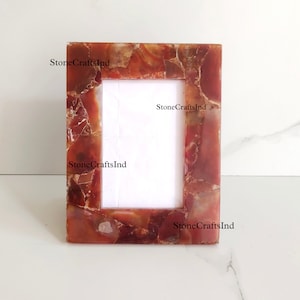 May include: A red agate picture frame with a white mat. The frame is made of natural stone and has a unique, organic look.