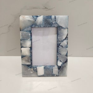 May include: A blue and white stone picture frame with a mosaic design. The frame is made of natural stone and has a rustic look.