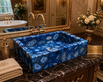 May include: A rectangular bathroom sink crafted from blue agate stone with concentric circular patterns. The sink features a polished finish and a central drain hole. A small gold-colored plaque with the text StoneCraftsInd is visible.
