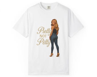 Könnte beinhalten: Weißes T-Shirt mit einer Grafik einer Frau in einem schwarzen Top und blauen Jeans, mit dem Text "Pretty Not Petty" in Gold. Die Frau trägt braune Absätze. Das Shirt hat einen Rundhalsausschnitt.