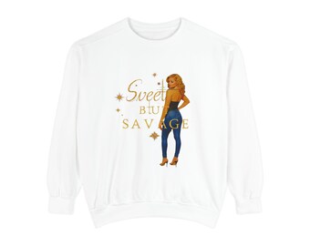 May include: White sweatshirt with a graphic of a woman in a black top and blue jeans. The text "Sweet but Savage" is in gold script and block letters, with star accents.