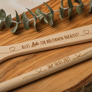 Könnte beinhalten: Zwei Holzlöffel mit eingravierten Herzen und Text. Der obere Löffel trägt die Aufschrift "Alles Liebe zur hölzernen Hochzeit!" und der untere Löffel trägt die Aufschrift "J&P 30.03.2019".