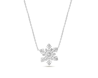 以下が含まれることがあります： 雪の結晶ペンダントが付いたシルバーカラーのネックレス。ペンダントは、小さく輝くアクセントで複雑にデザインされており、繊細でエレガントな冬をテーマにしたアクセサリーを作成しています。チェーンは細いシルバーリンクです。