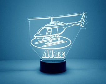 May include: A white outline of a helicopter with the name "Alex" underneath. The helicopter is on a black base.