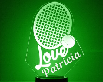 Op de afbeelding: Een wit verlicht nachtlampje in de vorm van een tennisracket met een tennisbal en de woorden "Love Patricia" erop.