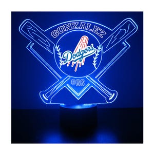 May include: A blue LED light featuring the name "GONZALEZ" and the "Dodgers" logo, with crossed baseball bats. The number "66" is displayed below the logo. The light is mounted on a dark base.