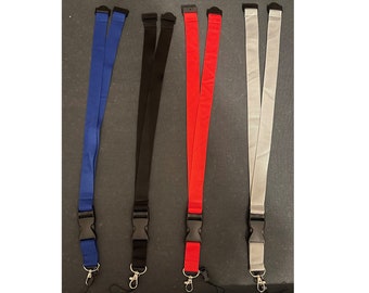May include: Four lanyards in blue, black, red, and gray. Each lanyard has a black plastic clasp and a metal hook. The lanyards are made of a smooth, flat material.