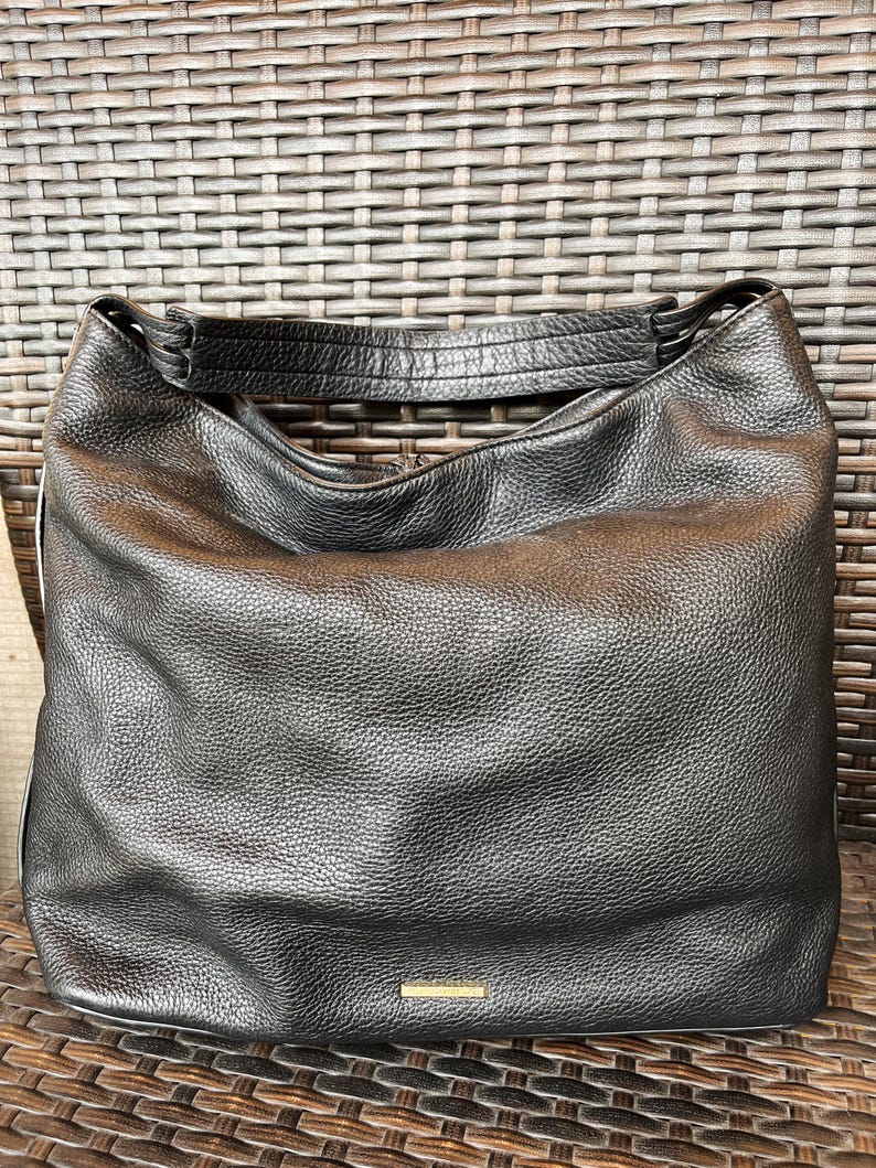 May include: Black leather hobo bag with a gold-toned logo on the front.