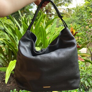 May include: Black leather hobo bag with a zipper closure and a single strap.