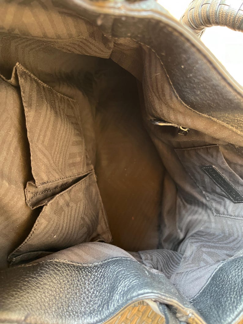 May include: The inside of a brown leather handbag with a zippered pocket and a brown patterned lining.