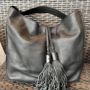 May include: Black leather hobo bag with a braided strap and two large tassels.