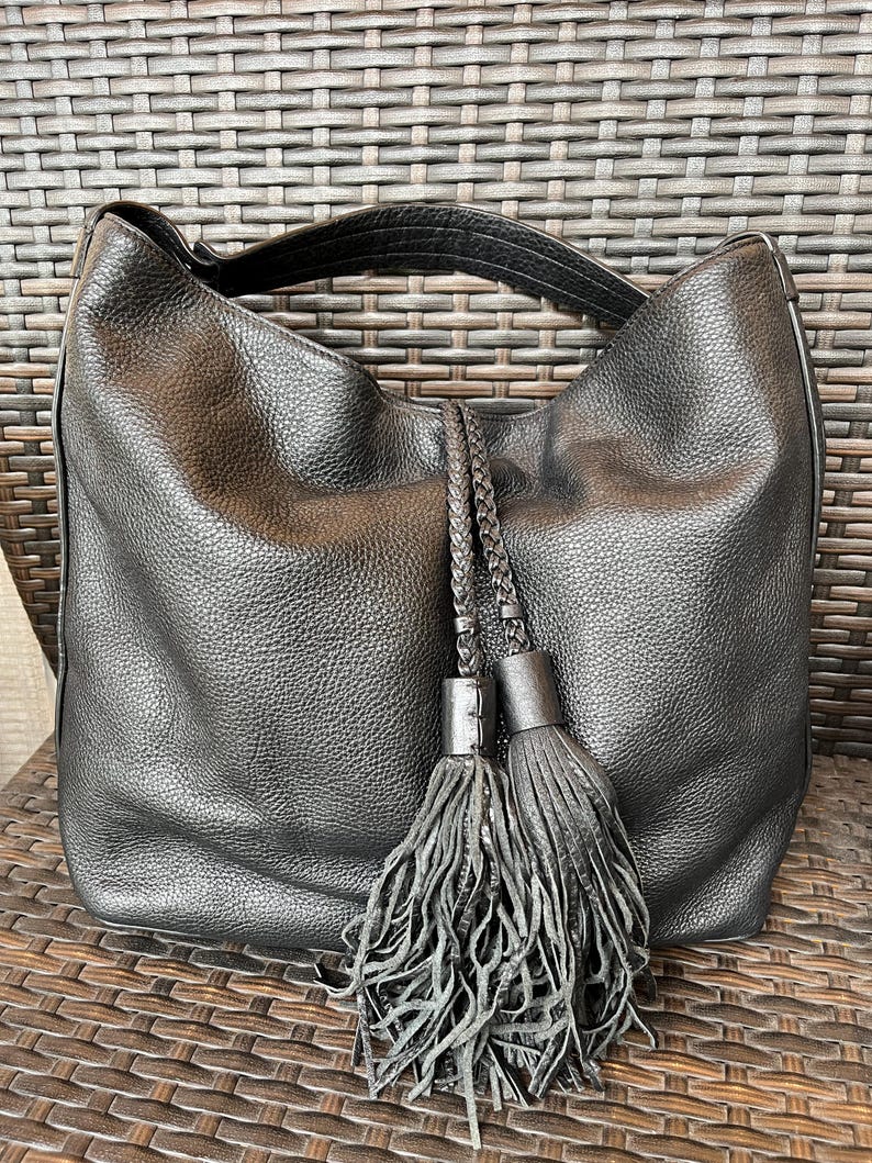 May include: Black leather hobo bag with a braided strap and two large tassels.