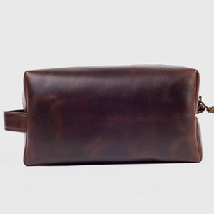 May include: A brown leather travel bag with a zip closure and a handle.