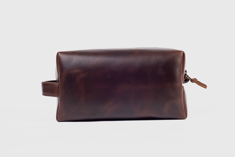 May include: A brown leather travel bag with a zip closure and a handle.