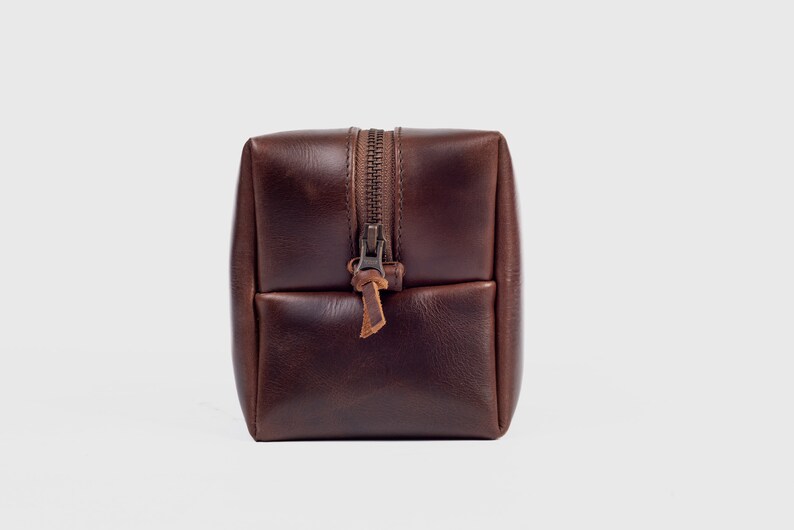 May include: A brown leather zippered wash bag with a brown leather zipper pull.