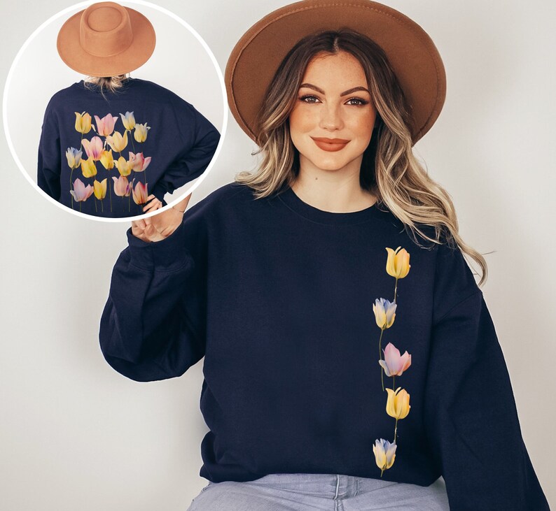 Peut inclure: Un sweat-shirt bleu marine avec une ligne verticale de tulipes color&eacute;es imprim&eacute;es sur le devant. Le sweat-shirt a un col rond et des manches longues.