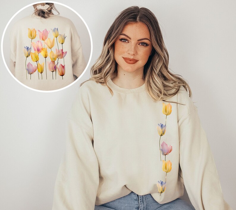 Peut inclure: Un sweat-shirt cr&egrave;me avec une ligne verticale de tulipes aquarelle dans des tons de rose, jaune et bleu sur le c&ocirc;t&eacute; gauche de la poitrine.