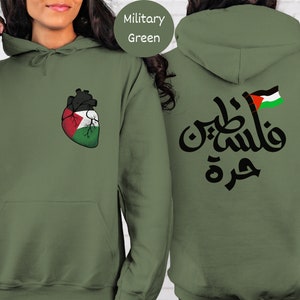 Może przedstawiać: Zielona bluza z kapturem w kolorze wojskowym z sercem w kształcie palestyńskiej flagi z przodu i arabskim napisem "فلسطين" z palestyńską flagą z tyłu.