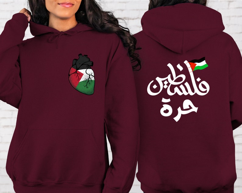 Może przedstawiać: Bordowa bluza z kapturem z nadrukiem w kształcie serca z flagą palestyńską z przodu i arabskim napisem "Palestyna" z flagą palestyńską z tyłu.