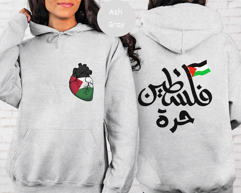 Może przedstawiać: Szara bluza z kapturem z sercem z flagą palestyńską z przodu i arabskim tekstem "فلسطين حرة" (Palestyna jest wolna) z flagą palestyńską z tyłu.