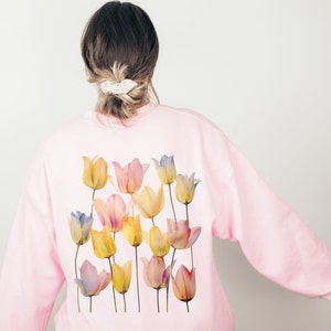 Peut inclure: Un sweat-shirt rose avec un motif aquarelle de tulipes jaunes, bleues et roses au dos.